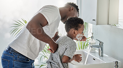 Buy stock photo Shot of a father washing shaving cream off his son's face in a bathroom at home