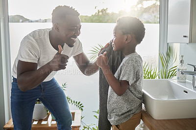 Buy stock photo Shot of a father showing thumbs up to his son while drying his face with a towel in a bathroom at home