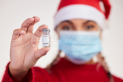 Buy stock photo Studio shot of a young woman holding vaccine and wearing a mask against a grey background