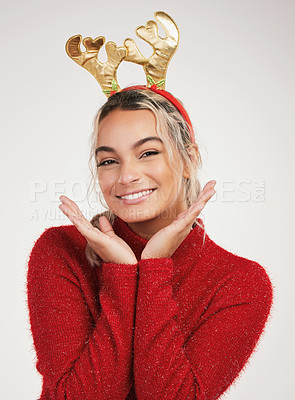 Buy stock photo Studio shot of a young woman wearing a reindeer headwear and posing  against a grey background