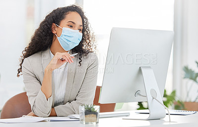 Buy stock photo Shot of a young businesswoman wearing a face mask while working on a computer in an office