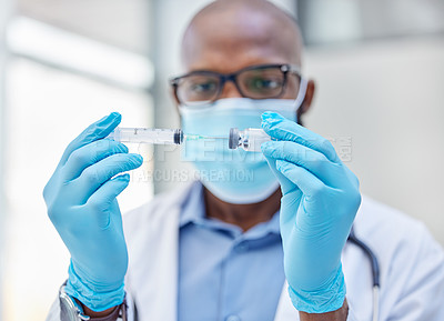 Buy stock photo Shot of a young doctor using a syringe to extract medication from a vial