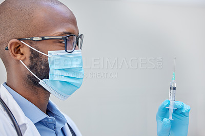 Buy stock photo Shot of a young doctor holding a syringe filled with liquid at work