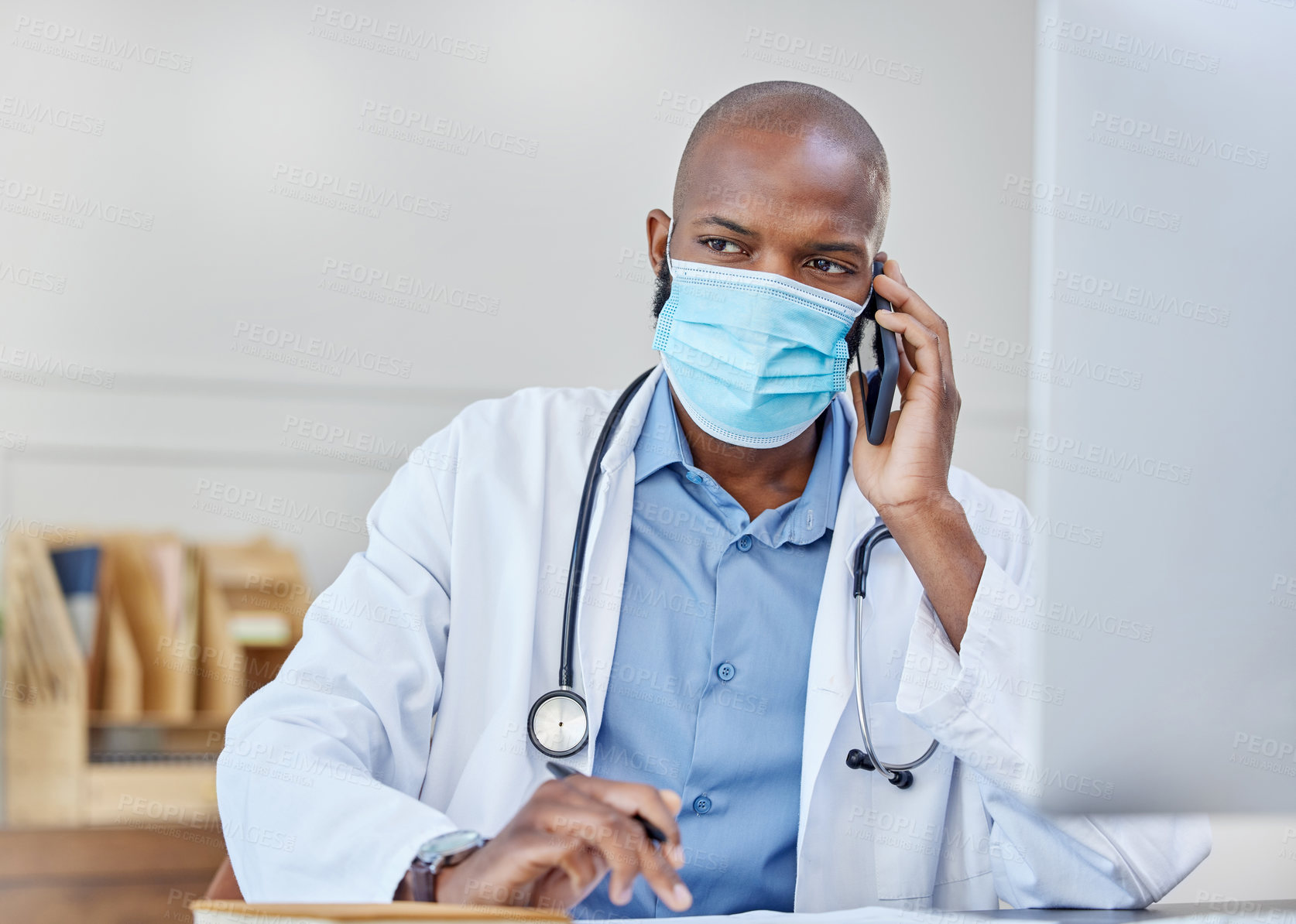 Buy stock photo Shot of a young doctor on a call while writing in a notebook at work