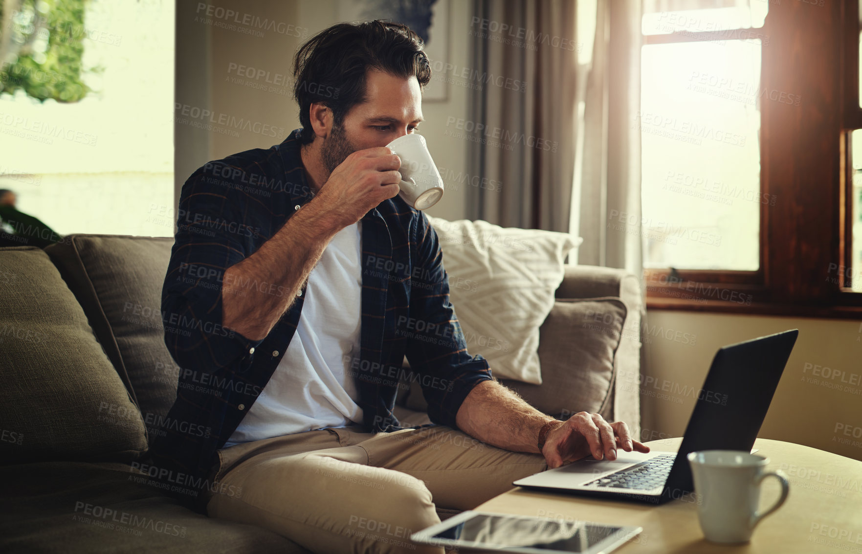 Buy stock photo Remote work, man or laptop in home drinking coffee, blog post or company review on internet. Male person, small business or technology in living room for contact, ecommerce or online feedback on sofa