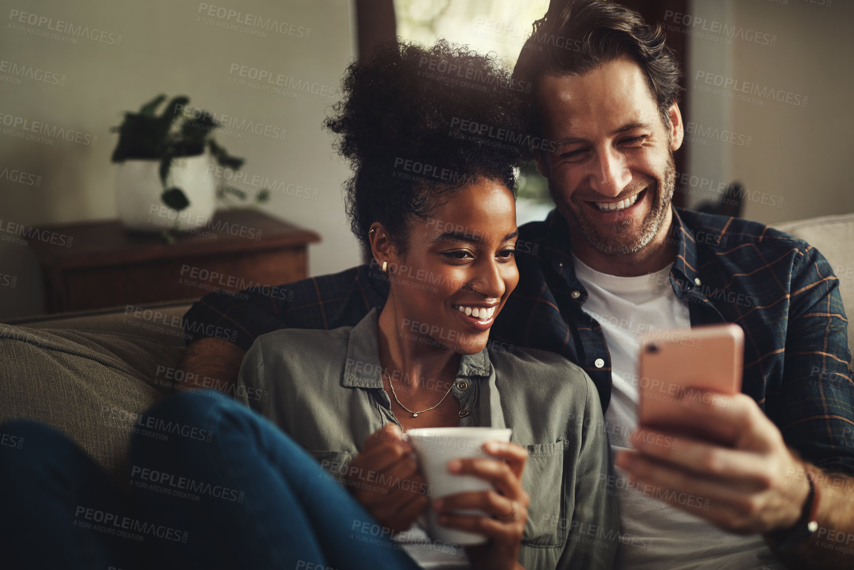 Buy stock photo Couple, smile and watch movie with cellphone, coffee and entertainment in morning and together on sofa in house. Digital, happy and love of woman with man, lounge and enjoyment in weekend in home