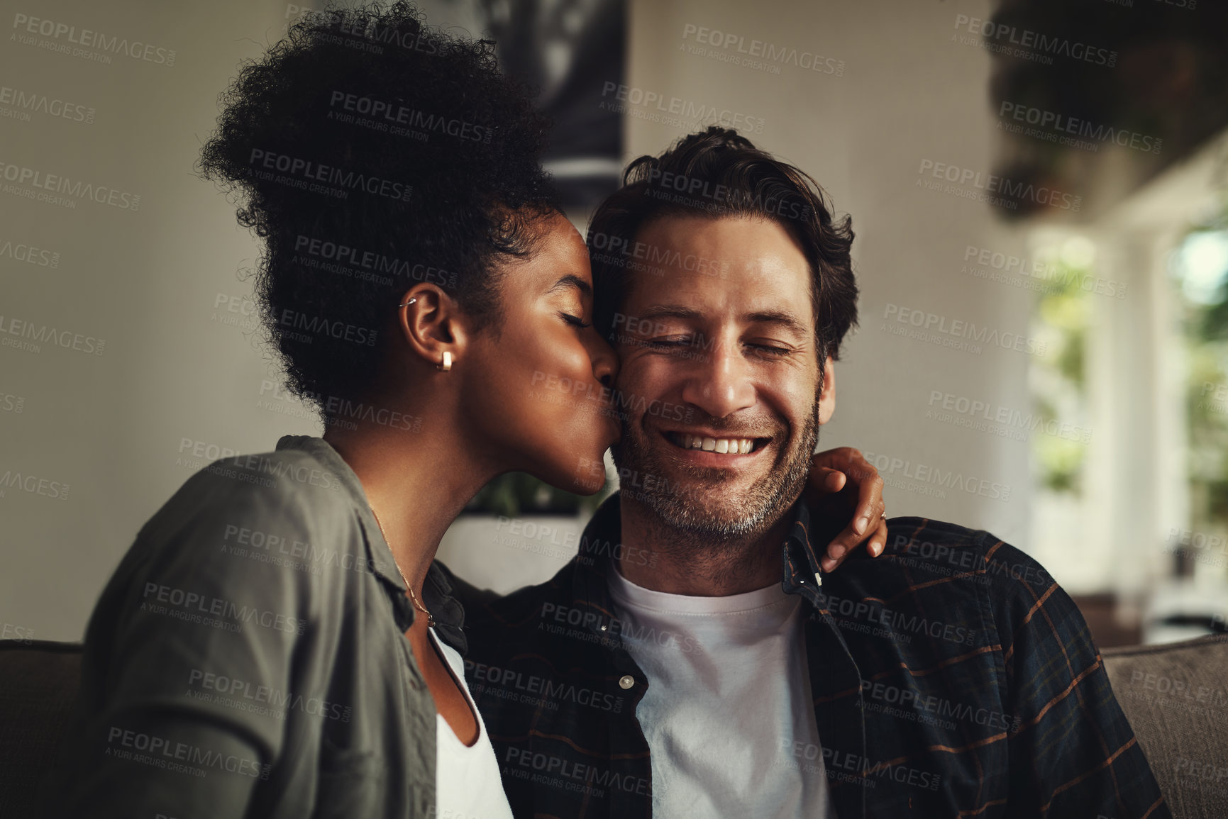 Buy stock photo Sofa, smile and couple with kiss on cheek for weekend romance, partnership and trust together. Happy, man and woman with affection at home on couch for love connection, support or bonding in marriage