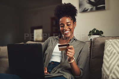 Buy stock photo Shot of a beautiful young woman using her credit card and laptop while relaxing on a sofa at home