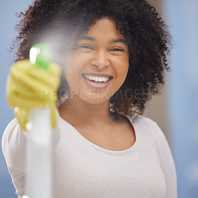 Buy stock photo Shot of an attractive young woman standing alone and spraying a bottle of detergent while doing the chores at home