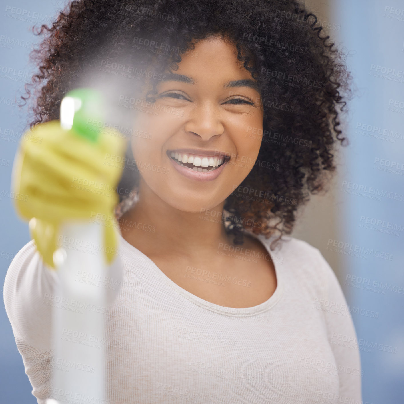 Buy stock photo Shot of an attractive young woman standing alone and spraying a bottle of detergent while doing the chores at home