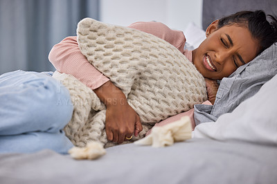 Buy stock photo Cropped shot of an attractive young woman lying on her bed at home while suffering from menstrual cramps