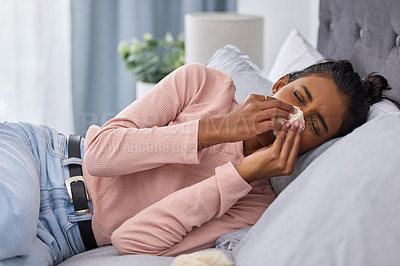 Buy stock photo Cropped shot of an attractive young woman lying on her bed at home while suffering from the flu