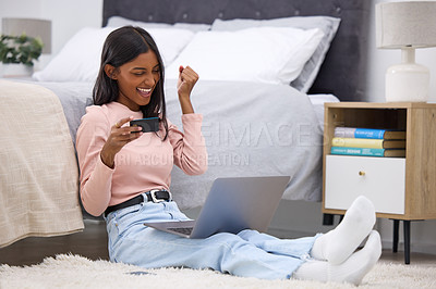 Buy stock photo Full length shot of an attractive young woman cheering while holding a credit card and using her laptop in the bedroom at home