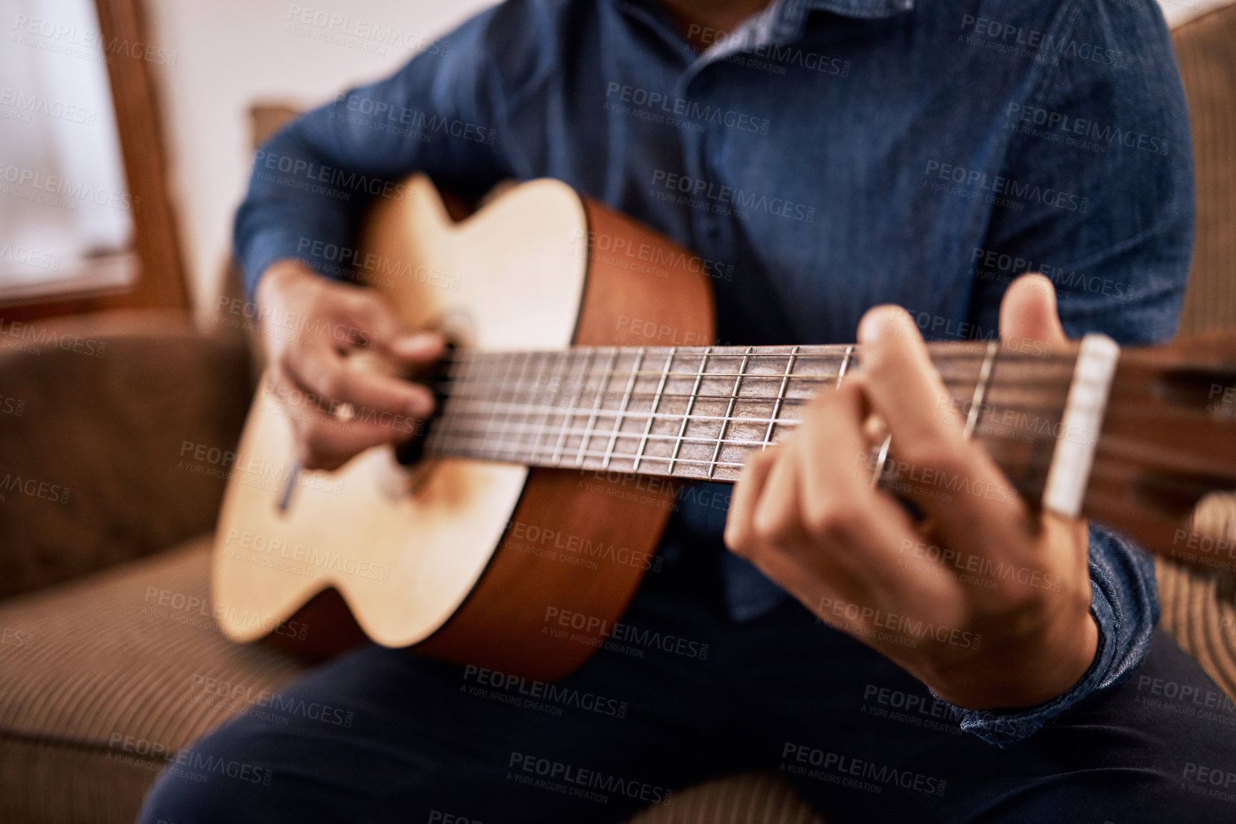 Buy stock photo Shot of a man practicing his guitar skills at home