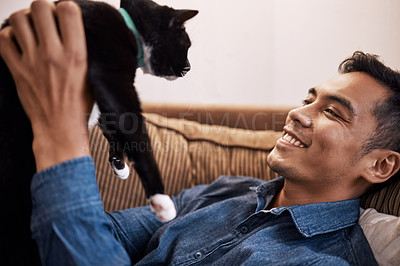 Buy stock photo Shot of a young man playing with his cat