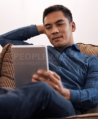 Buy stock photo Shot of a young man using his digital tablet at home