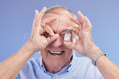 Buy stock photo Studio shot of a senior holding a vial filled with the COovid-19 vaccine against a blue background