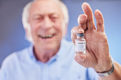 Buy stock photo Studio shot of a senior holding a vial filled with the COovid-19 vaccine against a blue background