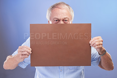 Buy stock photo Studio shot of a senior man holding a blank sign against a blue background