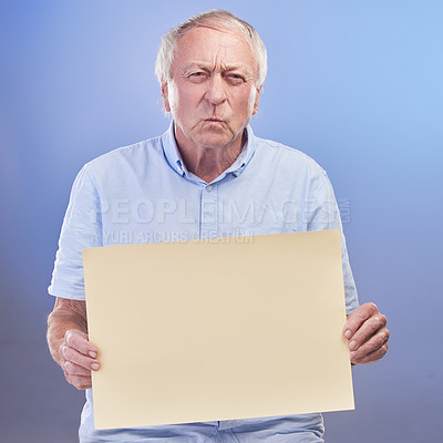 Buy stock photo Studio shot of a senior man holding a blank sign and looking unhappy against a blue background