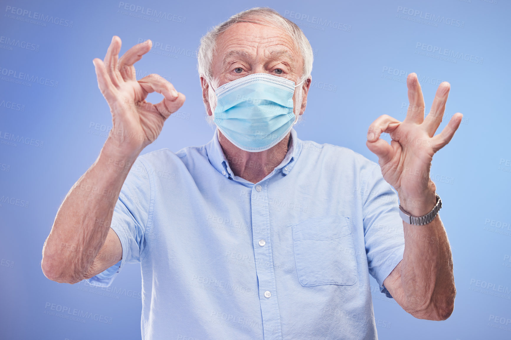 Buy stock photo Elderly man, portrait and okay for face mask in studio, promote healthcare and prevention of virus. Male person, emoji and insurance for wellness on blue background, protocol and protect against flu