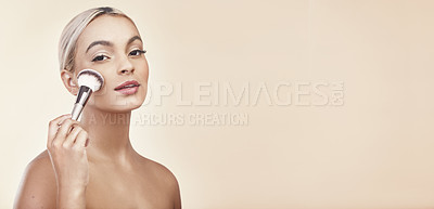 Buy stock photo Studio shot of a beautiful young woman holding a make-up brush against her face