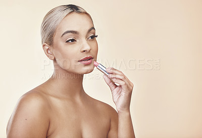 Buy stock photo Studio shot of a beautiful young woman applying pink lipstick