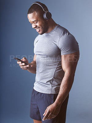 Buy stock photo Black man, headphones and phone for fitness in studio, exercise and audio for workout motivation. Happy male person, online and search playlist for sound, training and athlete on blue background