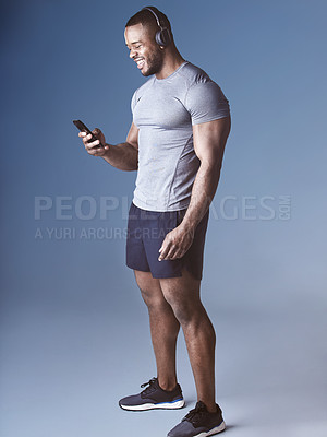 Buy stock photo Black man, headphones and phone for exercise in studio, wellness and audio for workout motivation. Happy male person, online and search playlist for sound, training and athlete on blue background