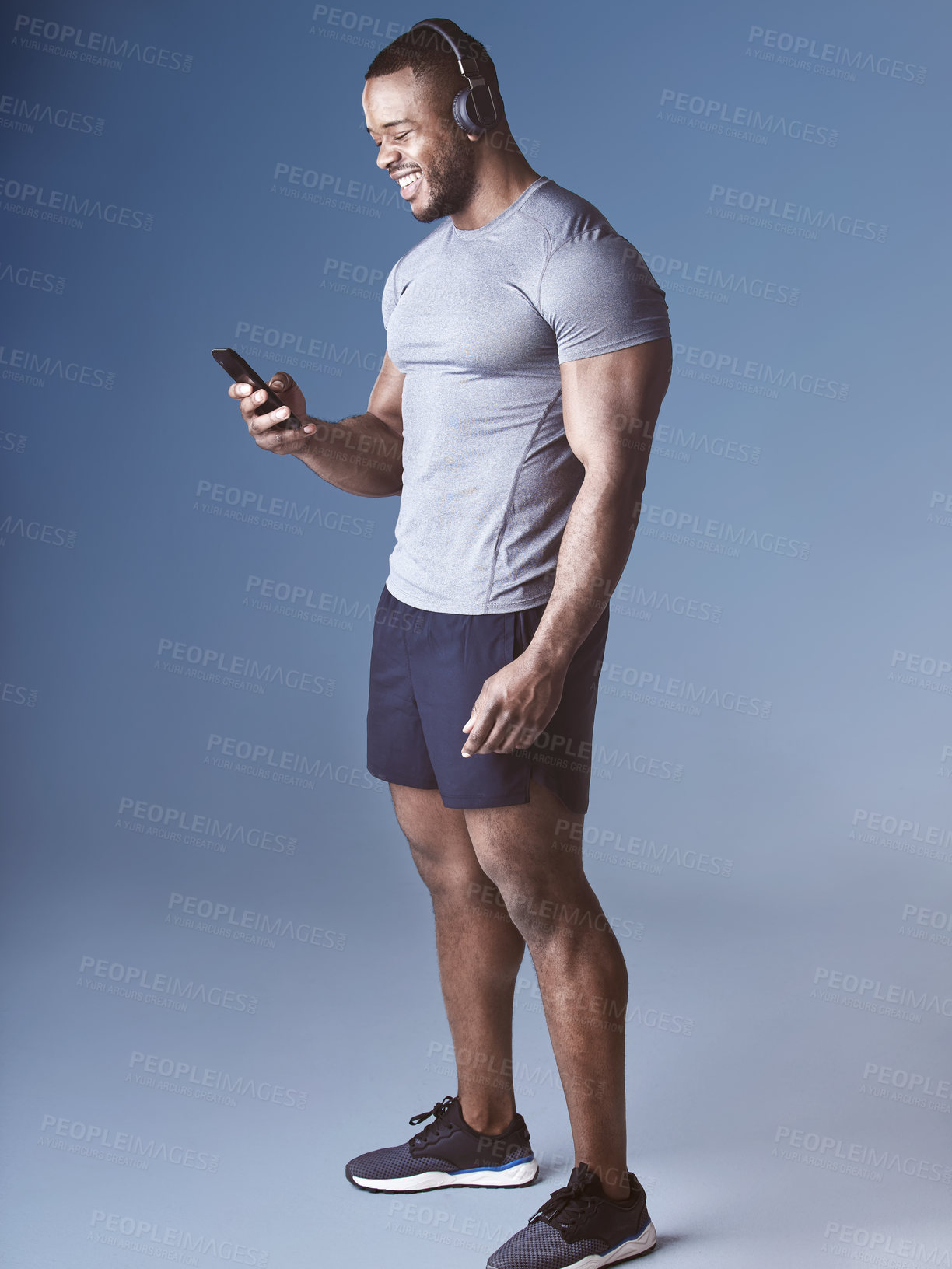 Buy stock photo Black man, headphones and phone for exercise in studio, wellness and audio for workout motivation. Happy male person, online and search playlist for sound, training and athlete on blue background