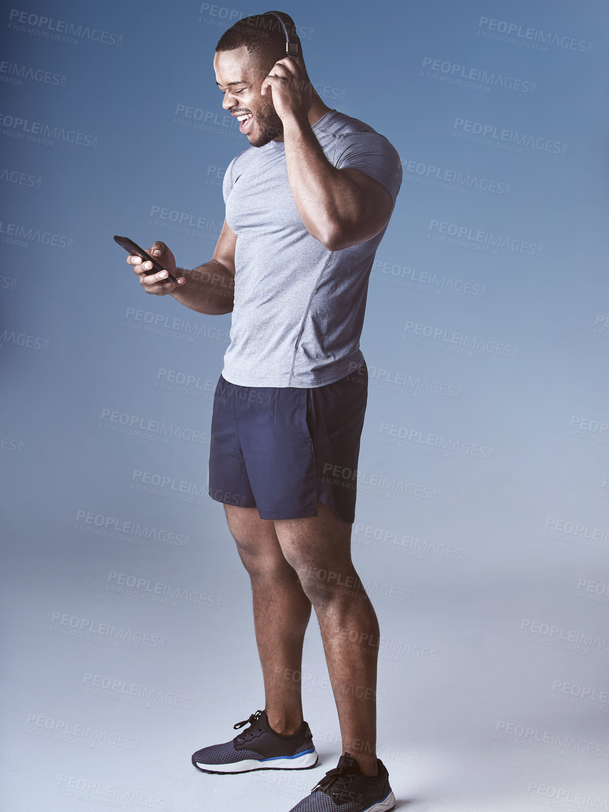 Buy stock photo Black man, headphones and happy for exercise in studio, wellness and audio for workout motivation. Male person, online and search playlist on phone for sound, song and athlete on blue background