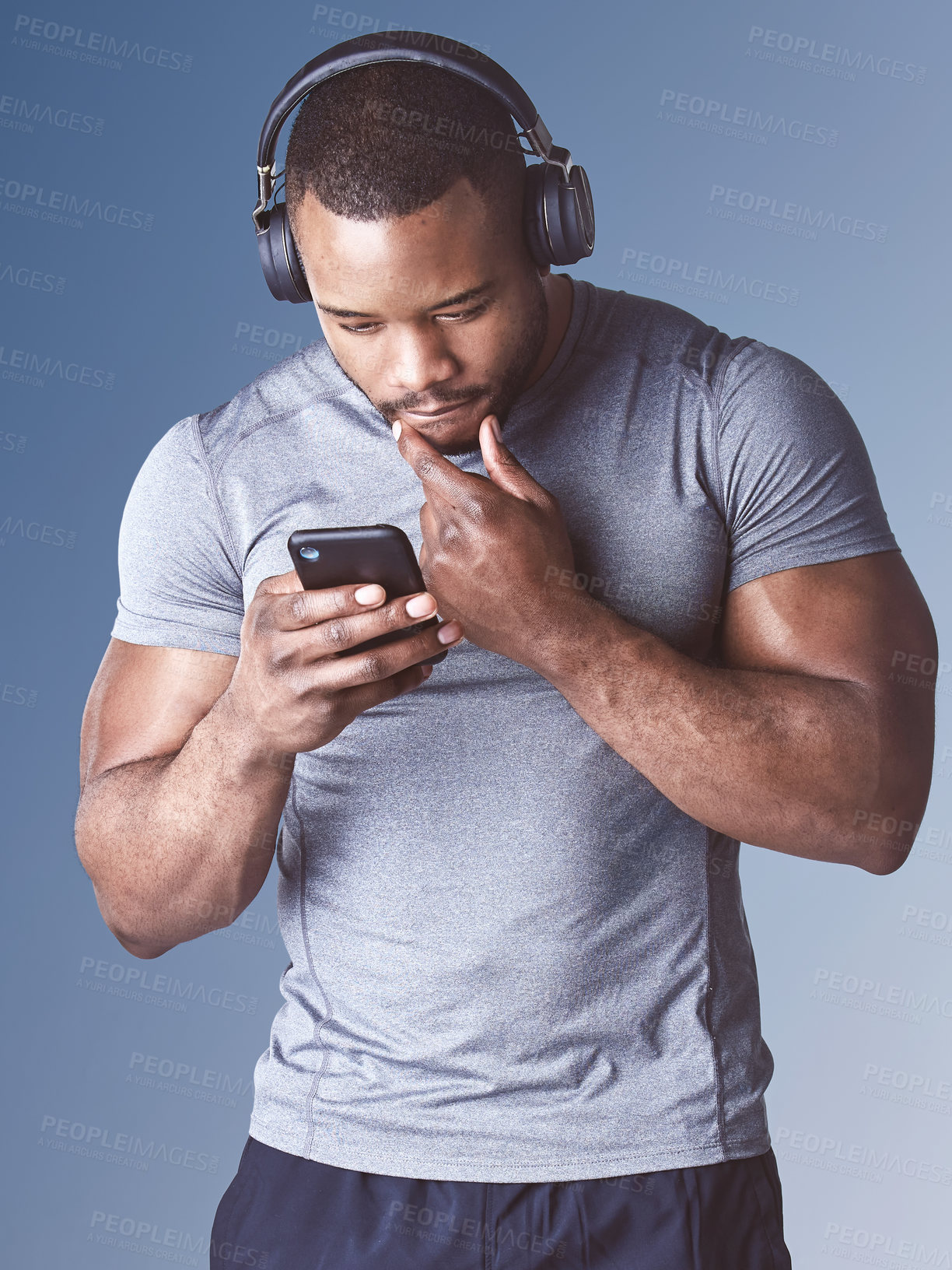 Buy stock photo Black man, headphones and workout app in studio, training schedule and online for song playlist. Male person, athlete and internet for fitness website, exercise and smartphone on blue background