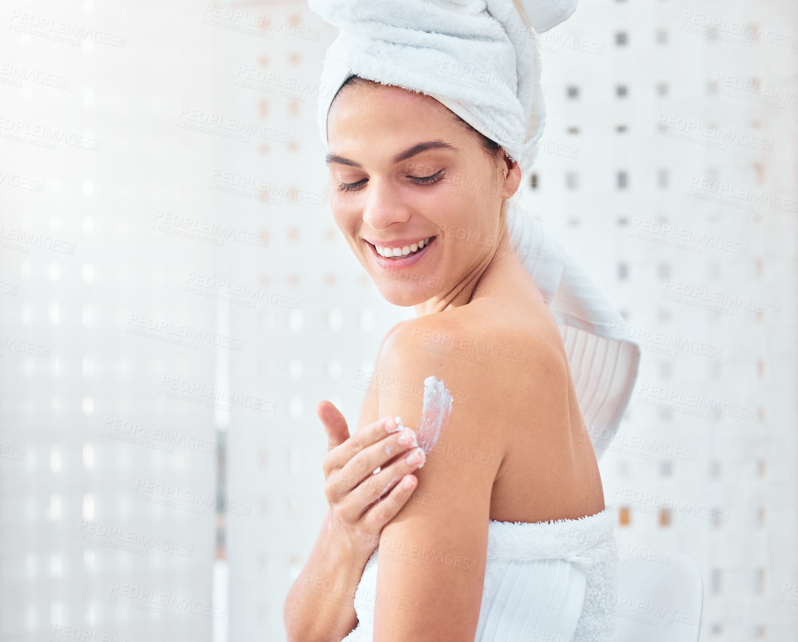 Buy stock photo Shot of a woman applying moisturiser to her arms and shoulders