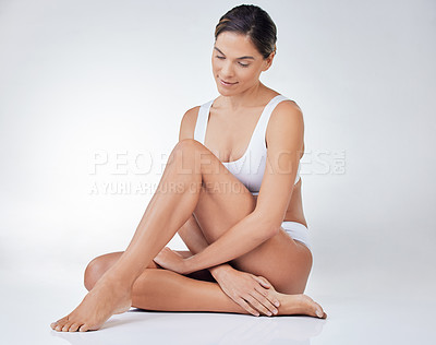 Buy stock photo Shot of a young woman sitting on the floor against a studio background