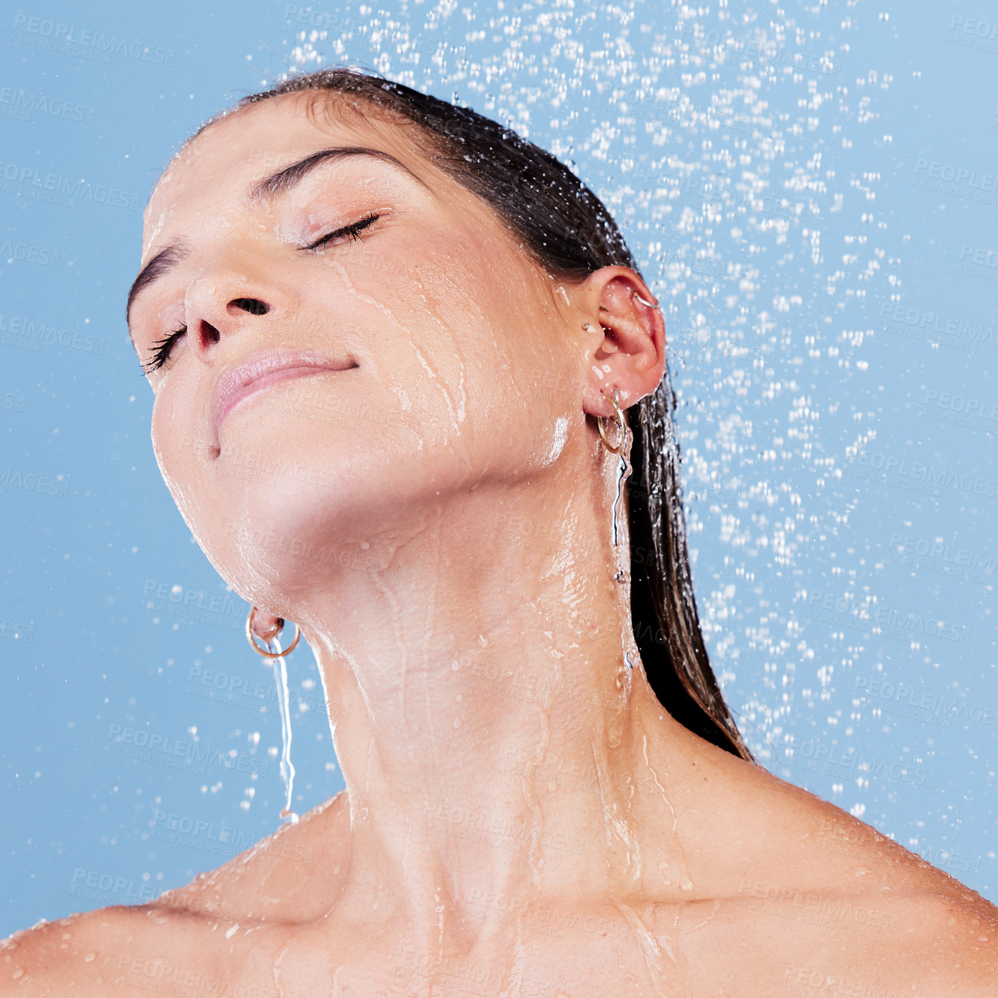 Buy stock photo Skincare, hair and woman in studio shower for wellness, cleaning and sustainable beauty routine on blue background. Water splash, face or girl model with haircare, shampoo and scalp, hygiene or detox