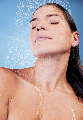 Buy stock photo Studio shot of a young woman taking a shower against a blue background