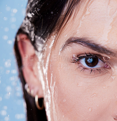 Buy stock photo Studio portrait of a young woman taking a shower against a blue background