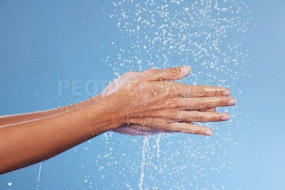 Buy stock photo Studio shot of an unrecognisable woman holding her hands under running water against a blue background