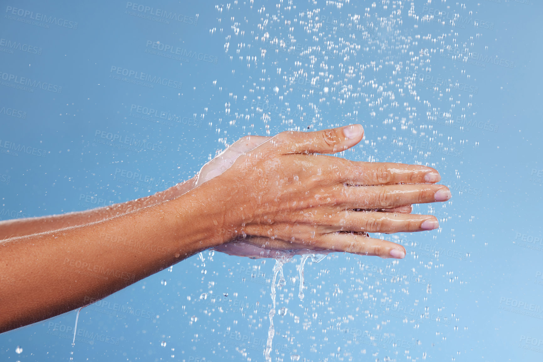 Buy stock photo Person, hands and water for germs in studio, washing and grooming for skincare on blue background. Palms, cleaning and liquid for cosmetics or bacteria and virus protection, disinfect and hydration