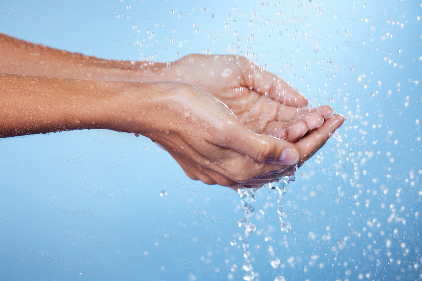 Buy stock photo Person, hands and water for cleaning in studio, washing and grooming for skincare on blue background. Palms, treatment and liquid for cosmetics or bacteria and protection, disinfect and hydration