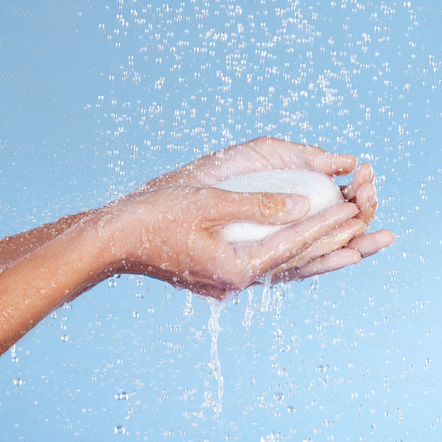 Buy stock photo Studio shot of an unrecognisable woman holding a bar of soap while taking a shower against a blue background