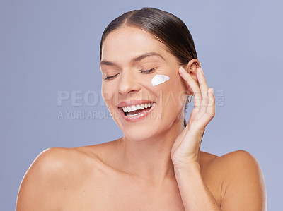 Buy stock photo Skincare, beauty and happy woman with face cream application in studio for wellness, dermatology or collagen on purple background. Smile, sunscreen and model with spf, lotion or facial acne treatment