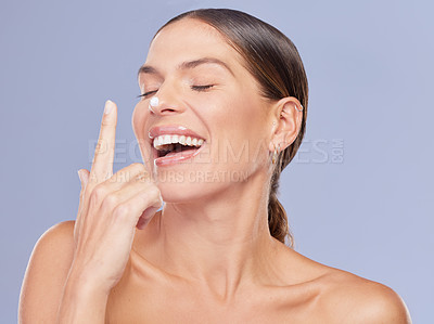 Buy stock photo Woman, nose and apply cream in studio for skincare, ointment and spf or cosmetics on blue background. Person, lotion and laugh for dermatology, glow and moisturizer for hydration or skin treatment