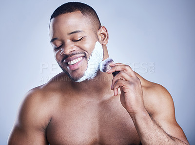Buy stock photo Studio shot of a handsome young man applying shaving foam to his beard against a blue background