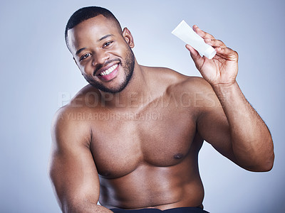 Buy stock photo Studio shot of a handsome young man applying moisturiser against a blue background