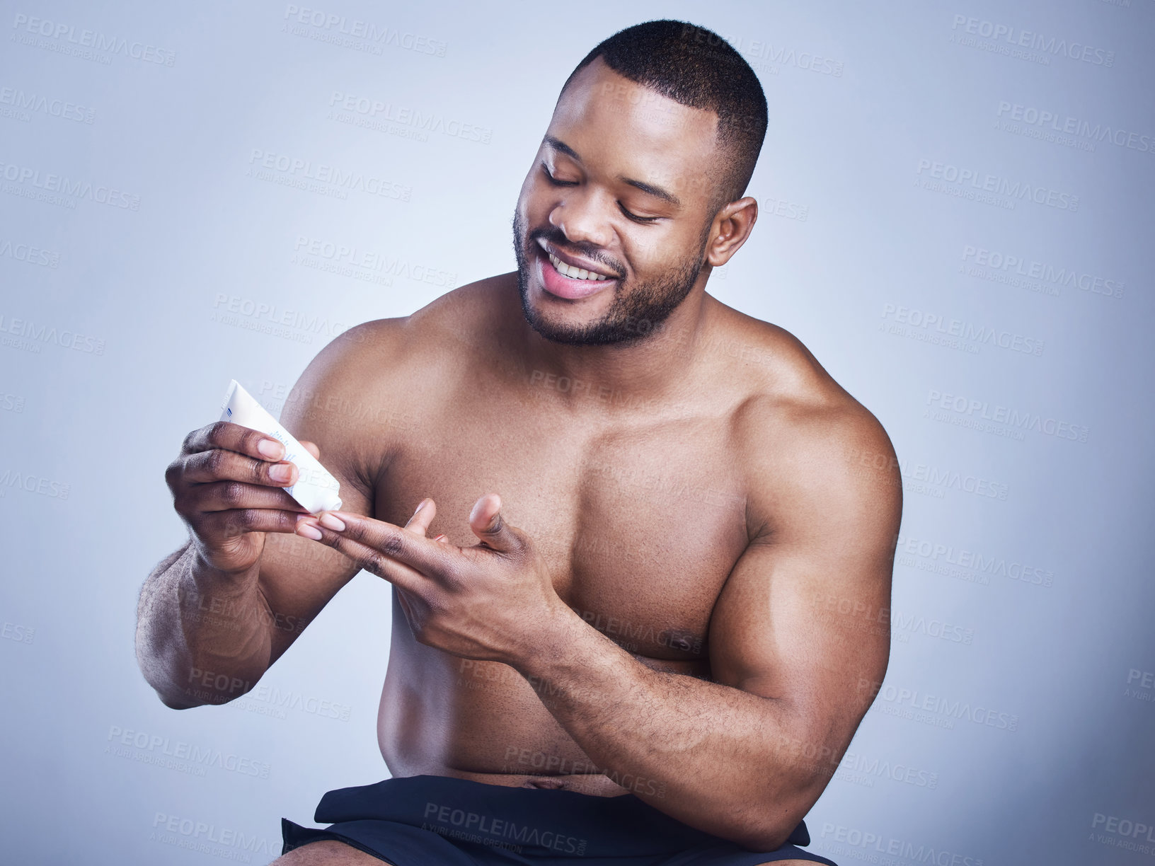 Buy stock photo Black man, tube and cream in studio for skincare, ointment and cosmetics on blue background. Person, apply and container for dermatology, sunscreen and moisturizer for hydration or skin treatment