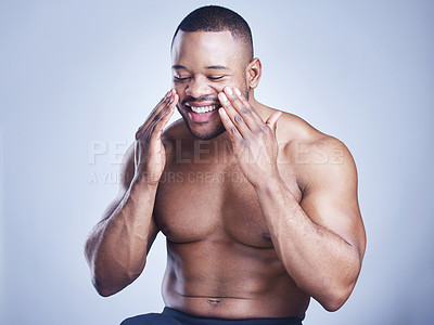 Buy stock photo Black man, apply cream and glow in studio for skincare, ointment and cosmetics on blue background. Person, lotion and pamper for dermatology, grooming and moisturizer for hydration or skin treatment