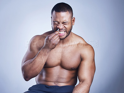 Buy stock photo Studio shot of a handsome young man plucking his nose hair against a grey background