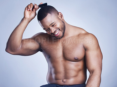 Buy stock photo Studio shot of a handsome young man brushing his hair against a blue background