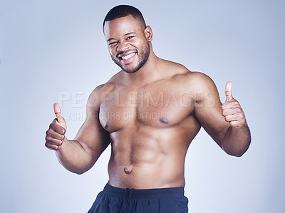 Buy stock photo Studio shot of a handsome young man showing thumbs up against a grey background